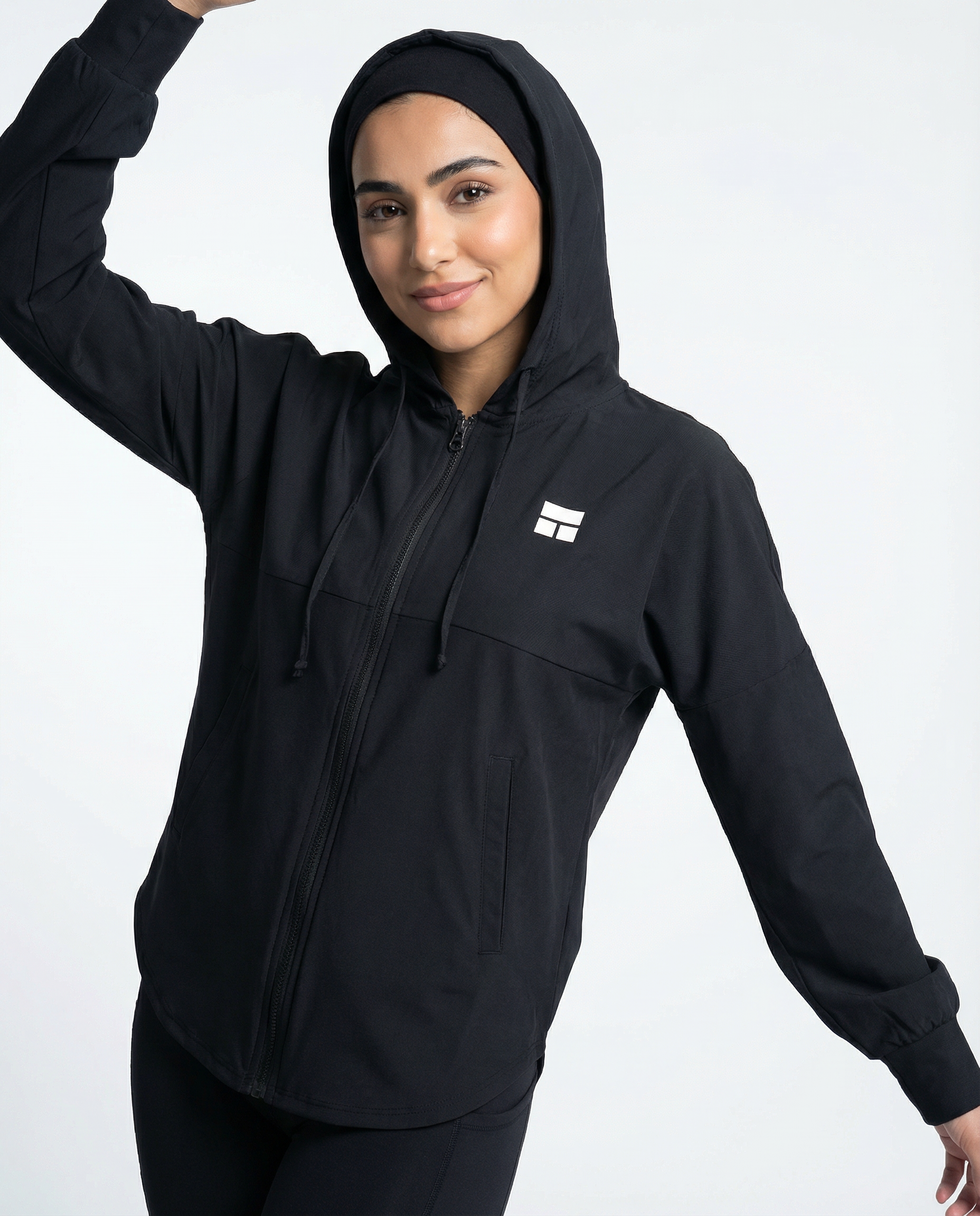 Person wearing a black hooded jacket with a logo on a white background