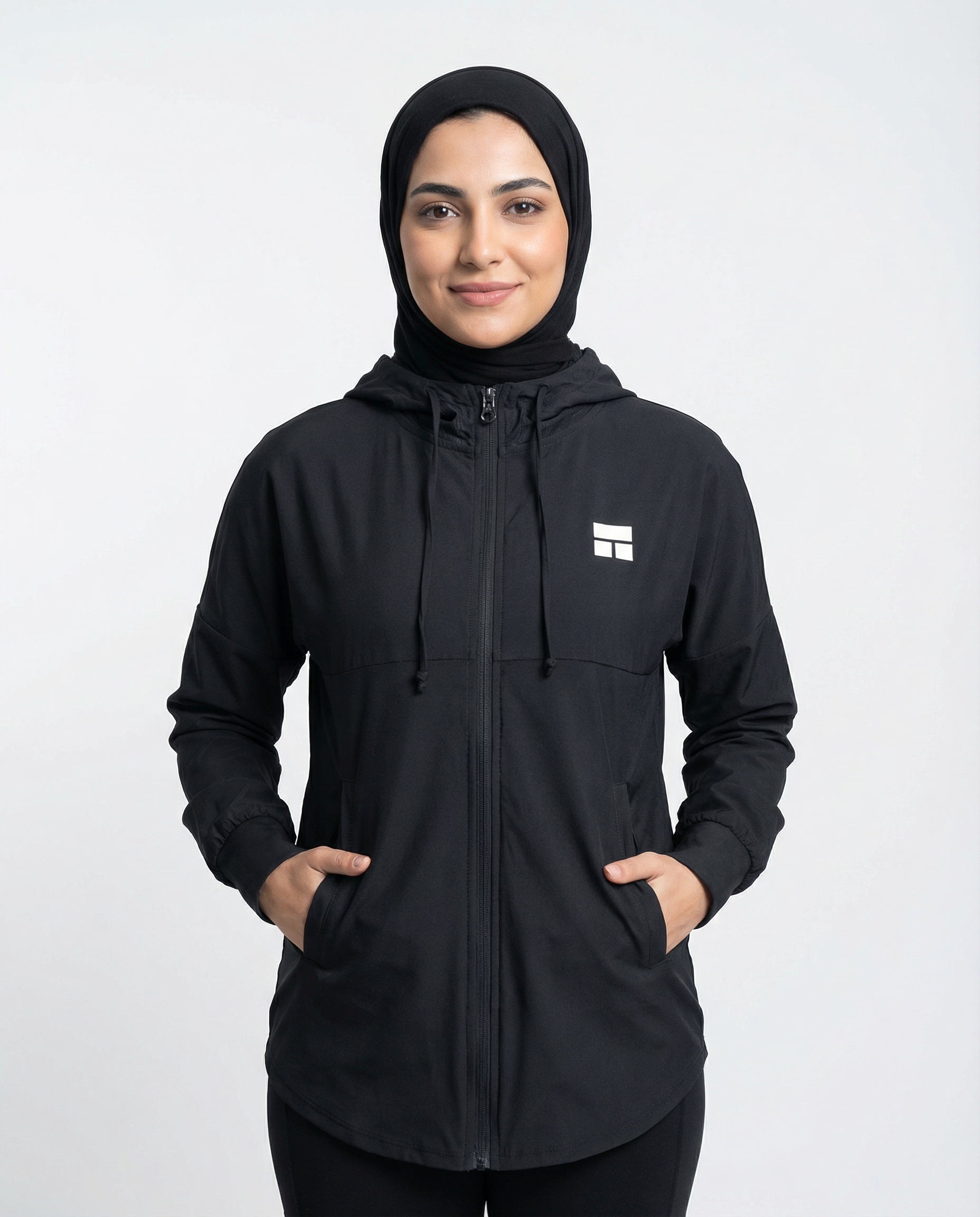 Person wearing a black hooded jacket with a logo on a white background