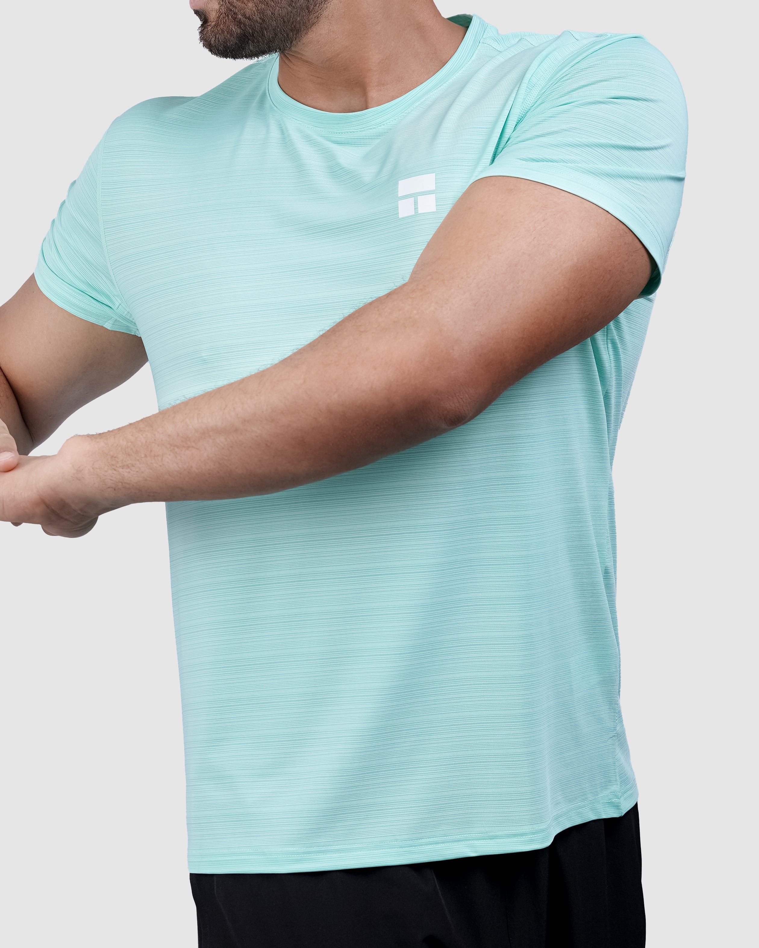 Man wearing a light blue t-shirt and black shorts on a white background