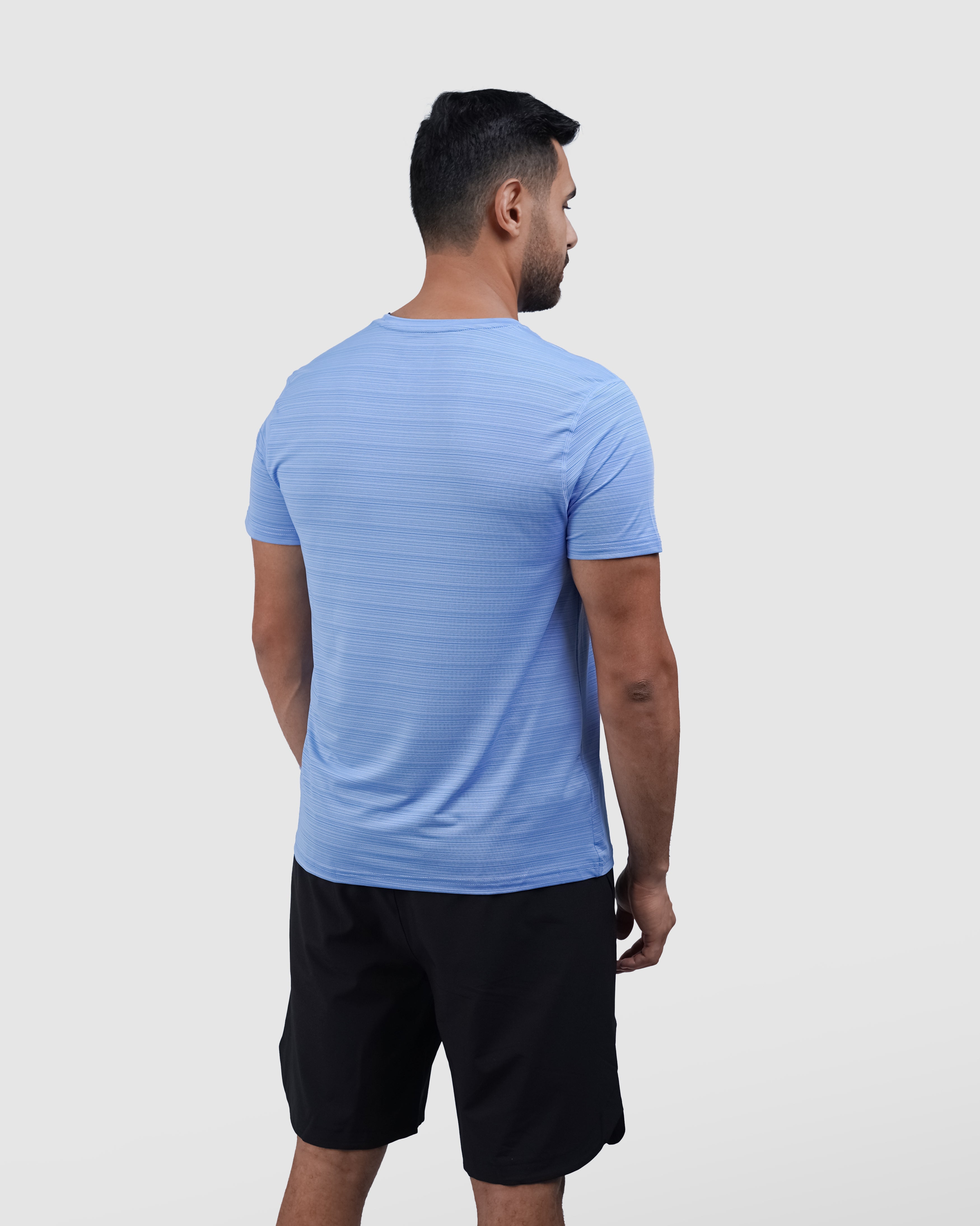 Man wearing a blue athletic shirt with a logo on a light gray background