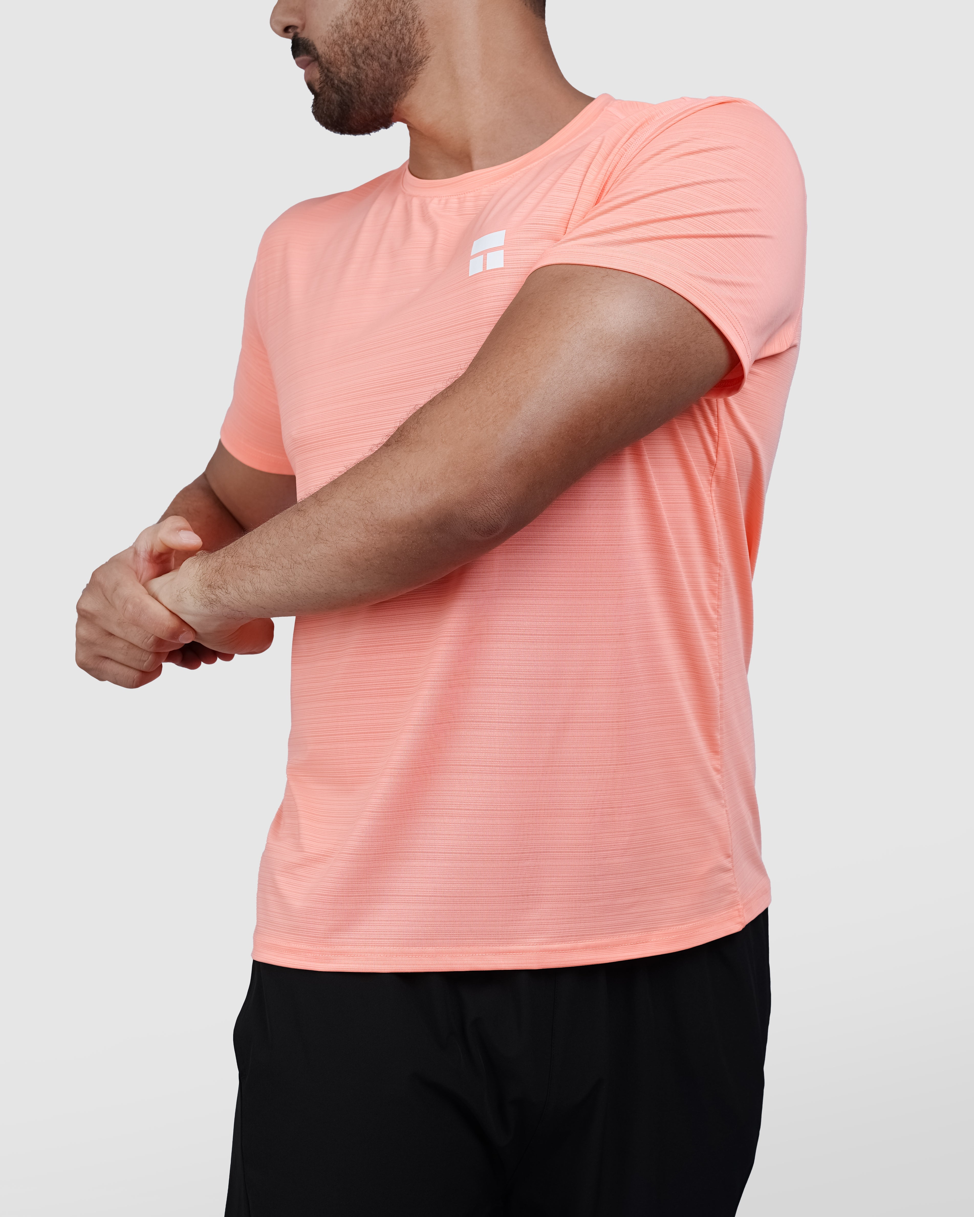 Man wearing a peach t-shirt and black shorts on a white background