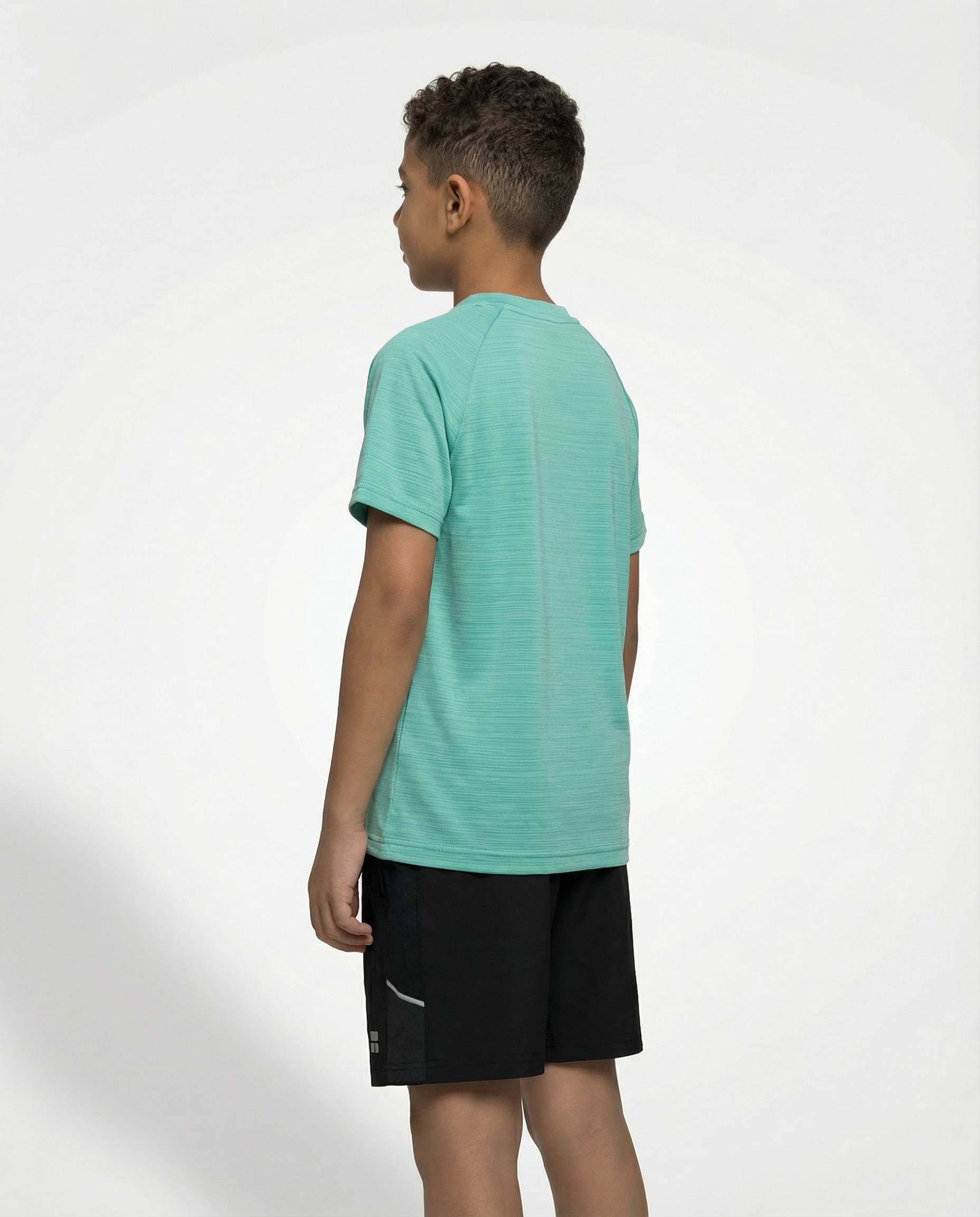 Child wearing a Courts green t-shirt and black shorts on a white background