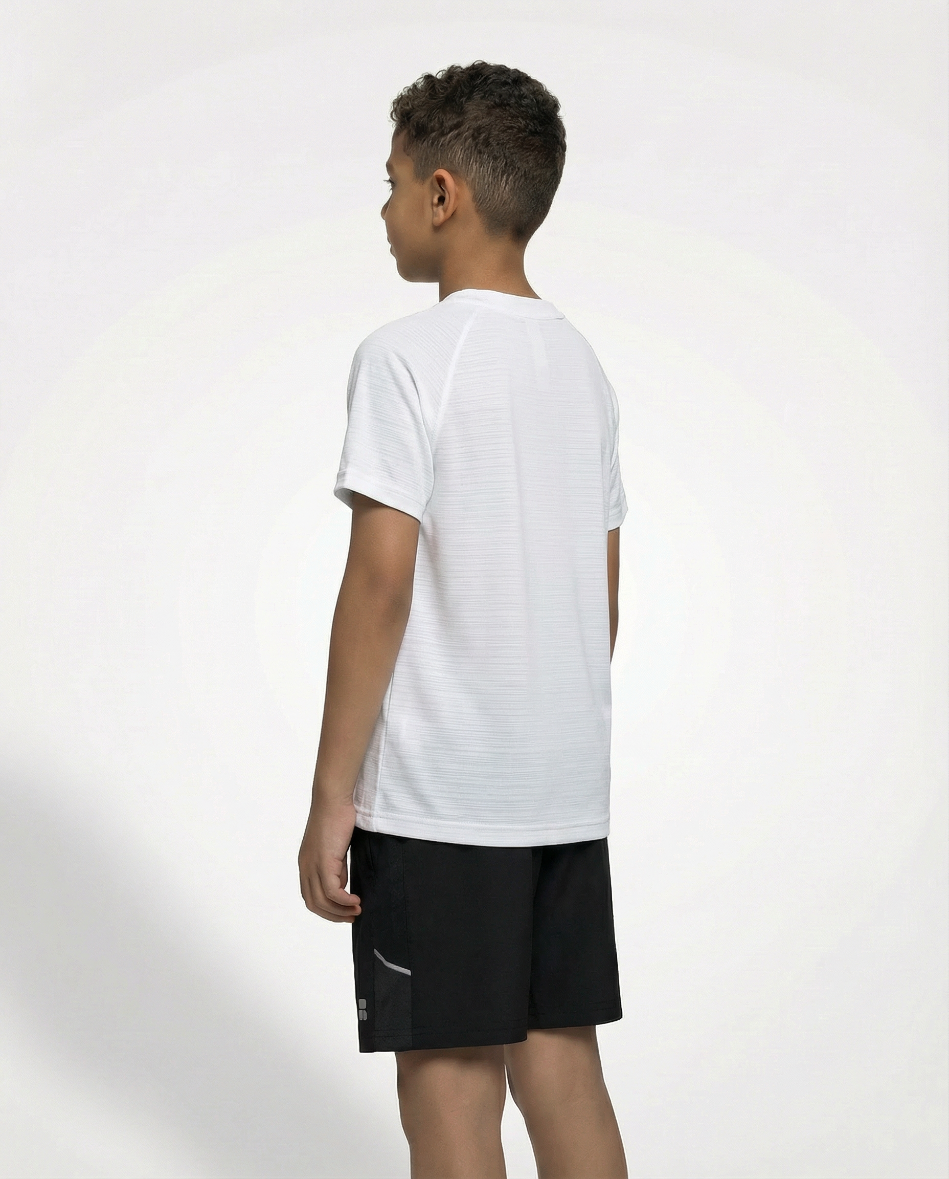 Child wearing a Courts sport white t-shirt and black shorts on a white background