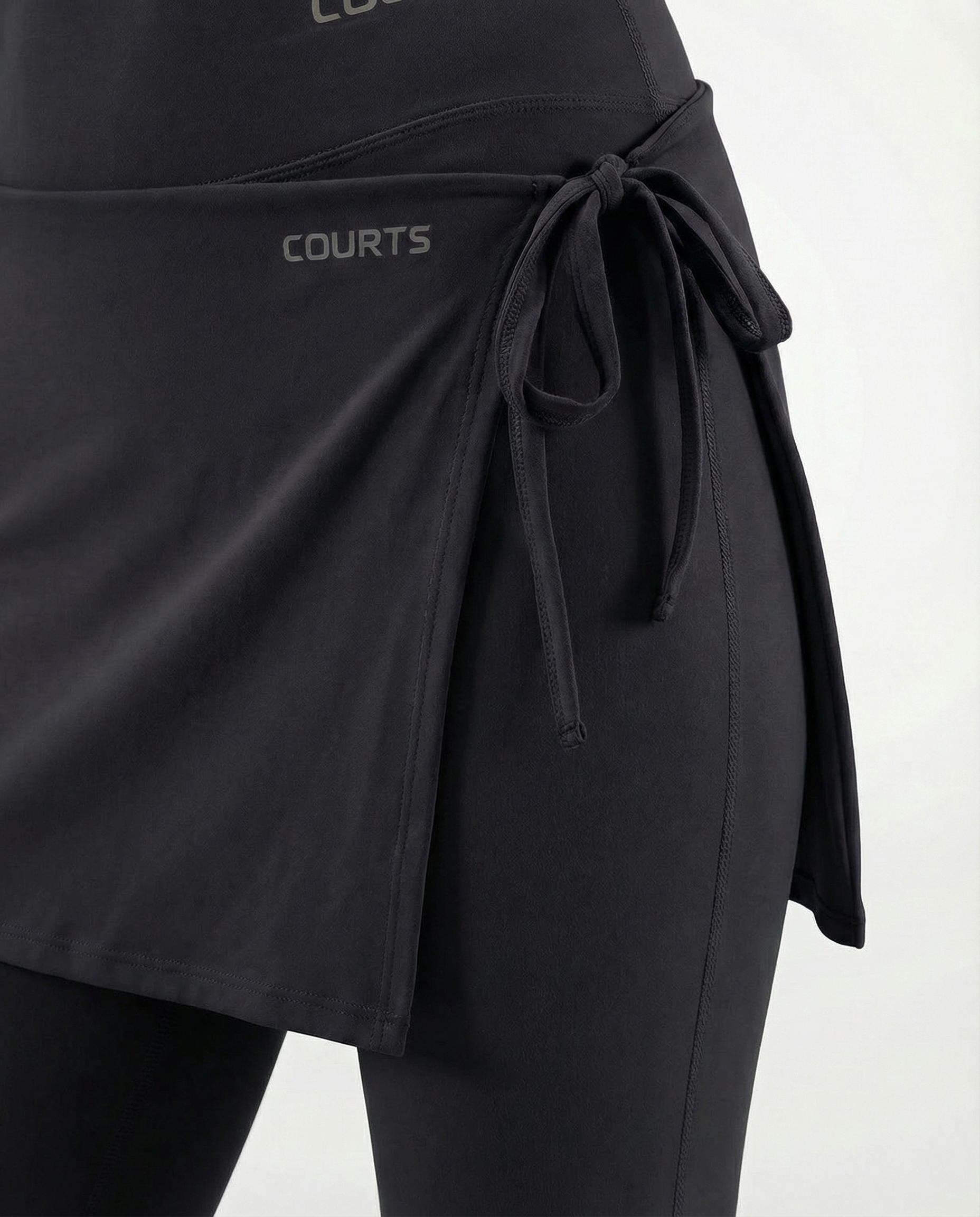 Mannequin wearing a black skirt and pants with 'Courts' branding on a white background