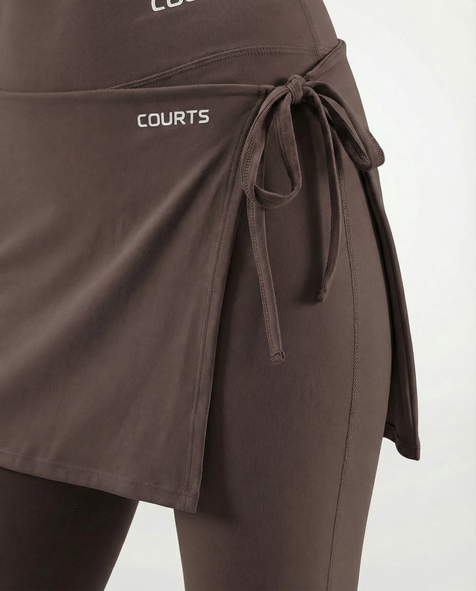 Mannequin wearing a brown skirt and pants with 'Courts' branding on a white background