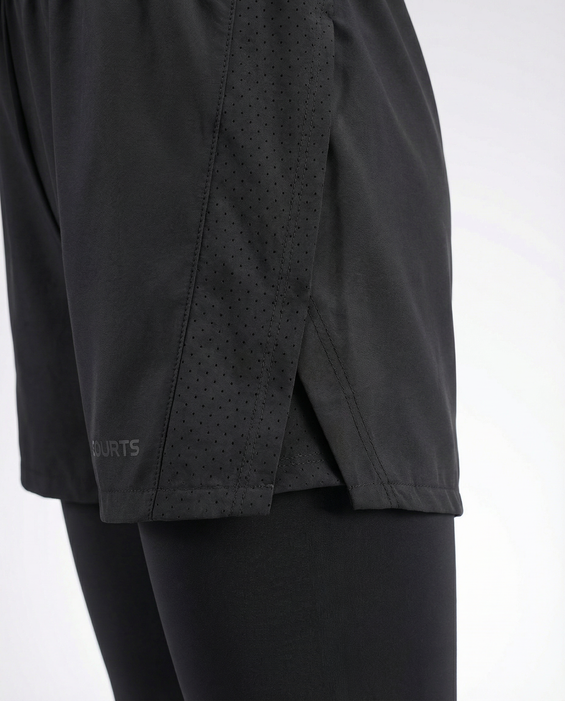 Mannequin wearing black athletic shorts and leggings with white sneakers on a light gray background