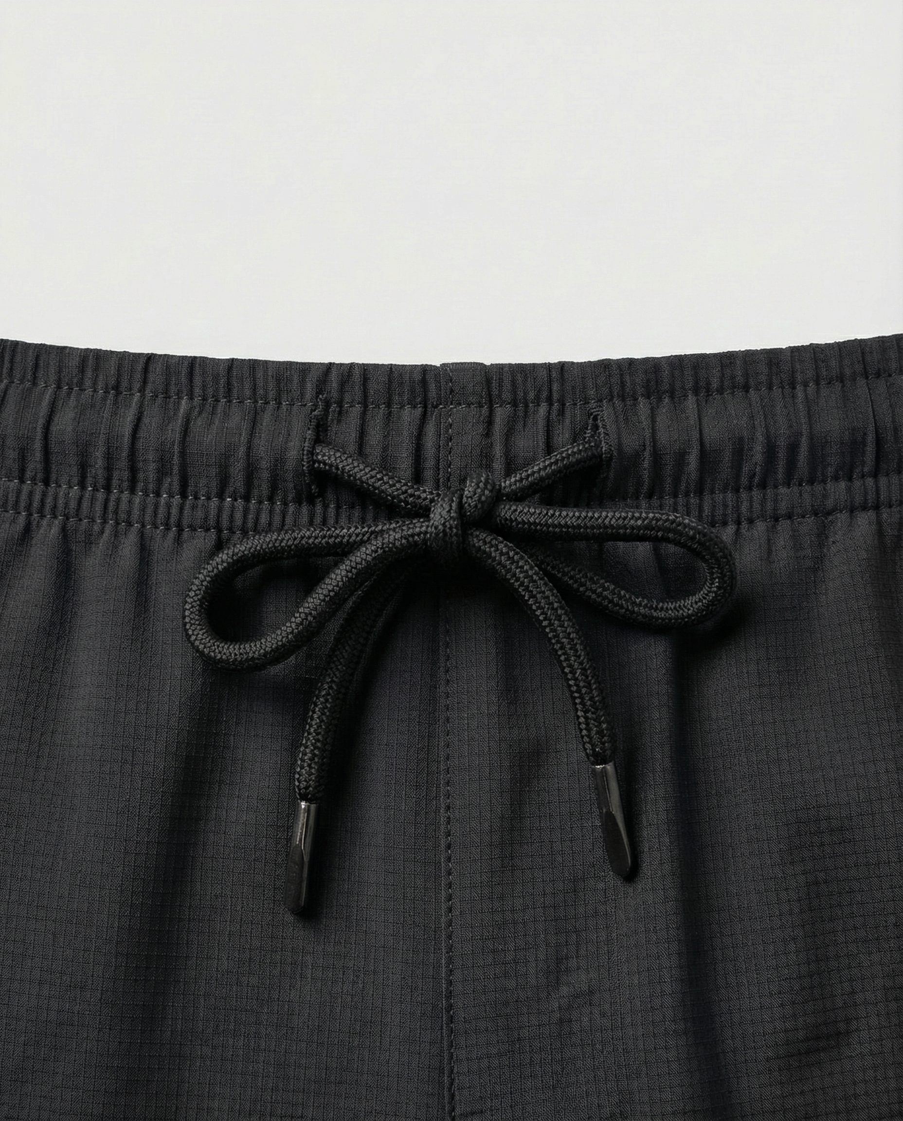 Person wearing courts sport black shorts with a white background