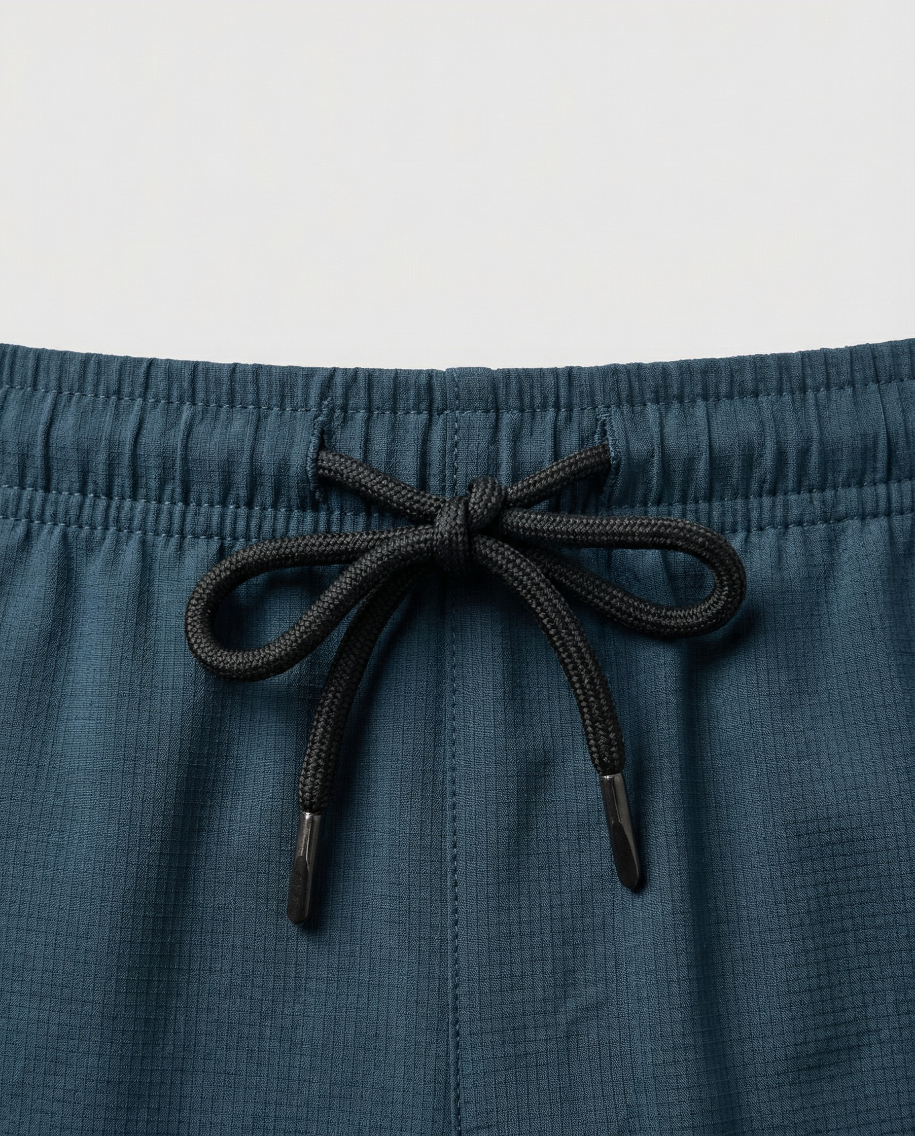 Person wearing haze blue athletic shorts with a visible Courts brand logo on a white background