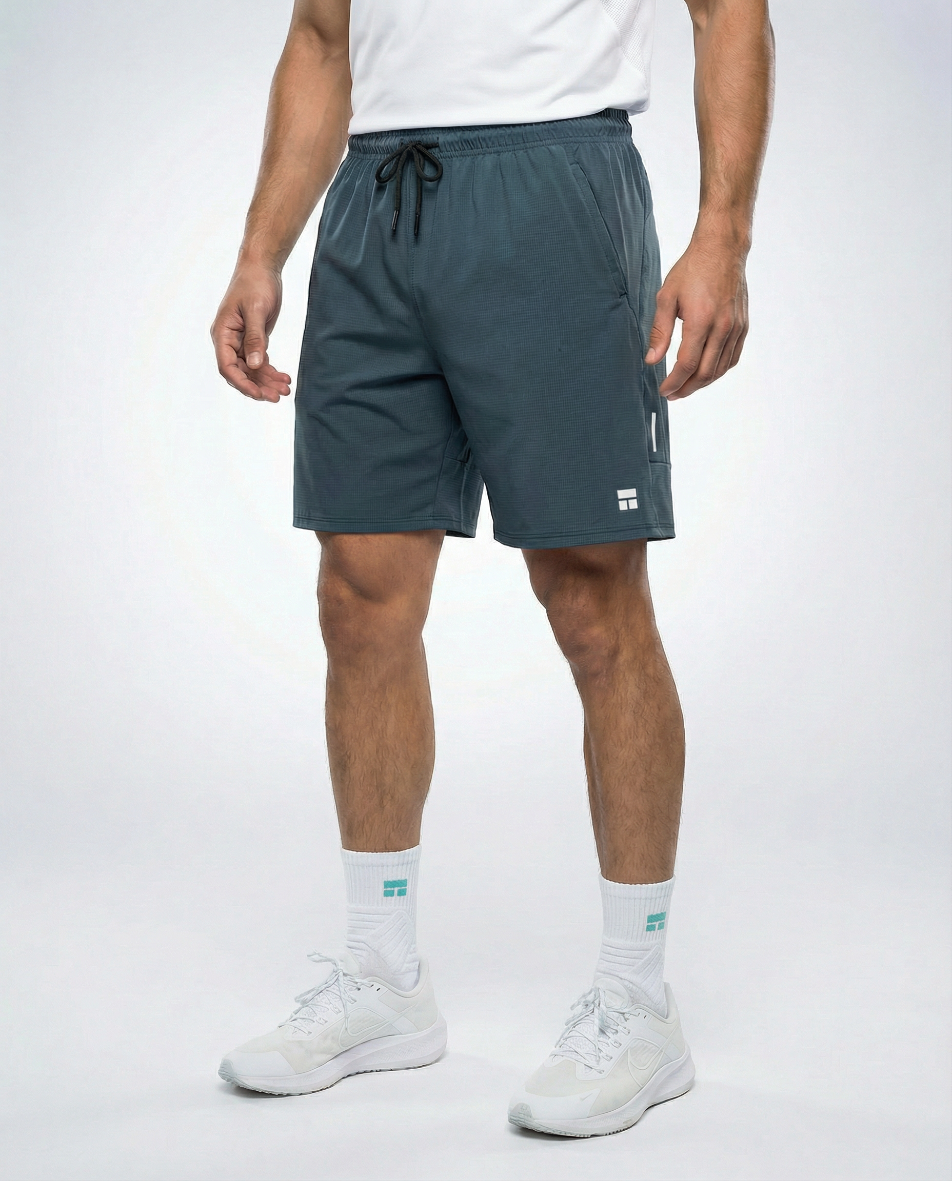 Person wearing haze blue athletic shorts with a visible Courts brand logo on a white background
