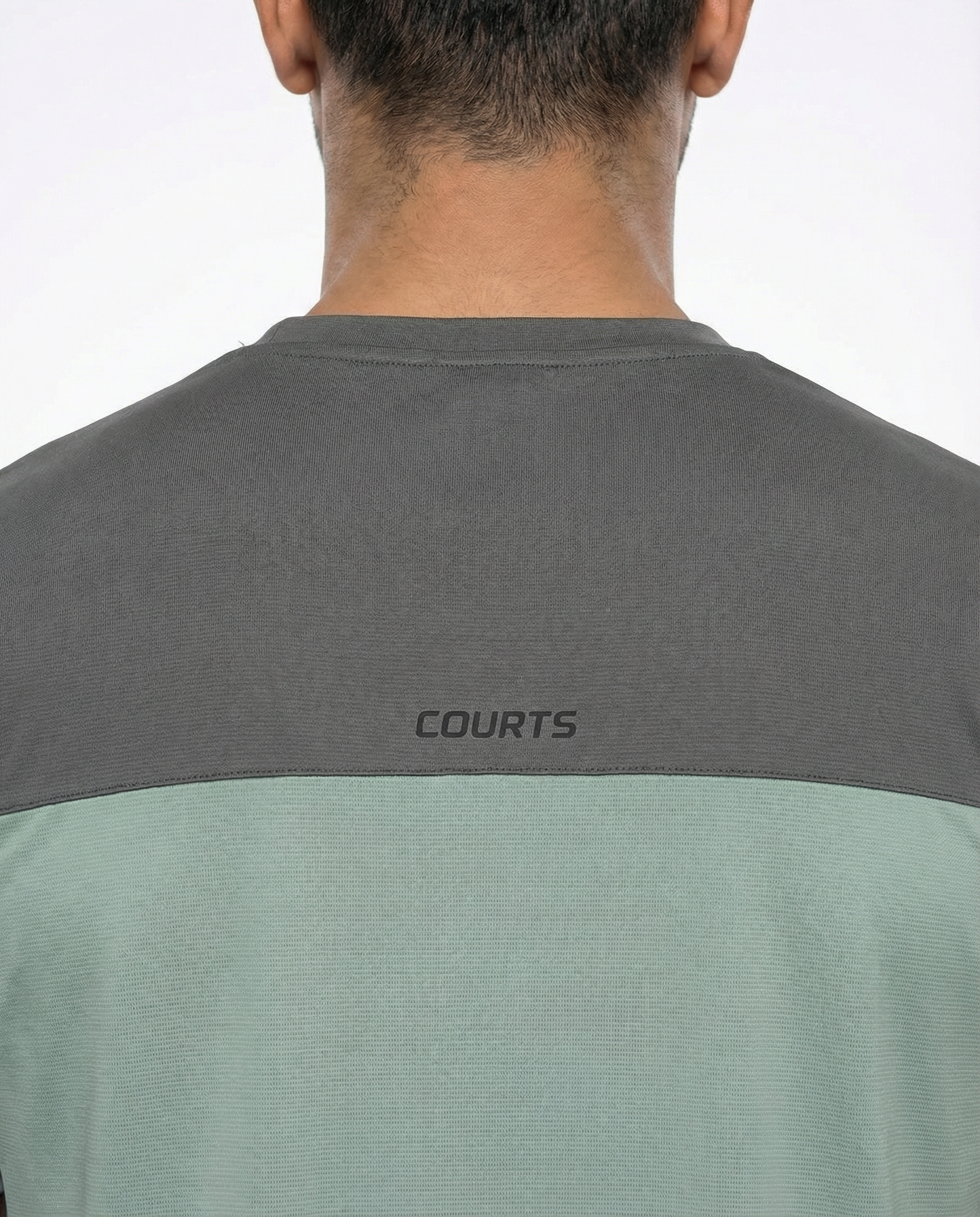 Man wearing a green athletic shirt with a logo on a white background
Courts Sport