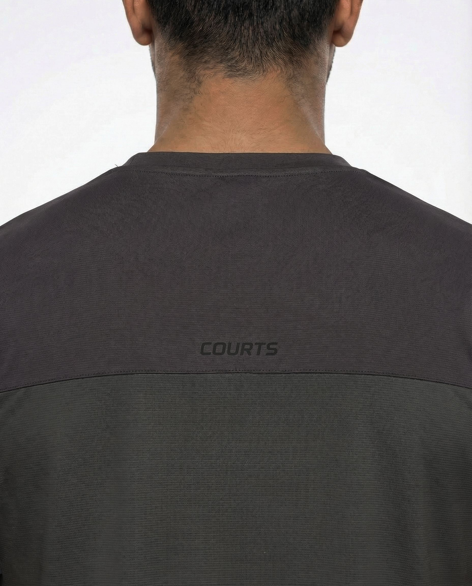 Man wearing a dark gray athletic shirt with black sleeves on a white background
Courts Sport