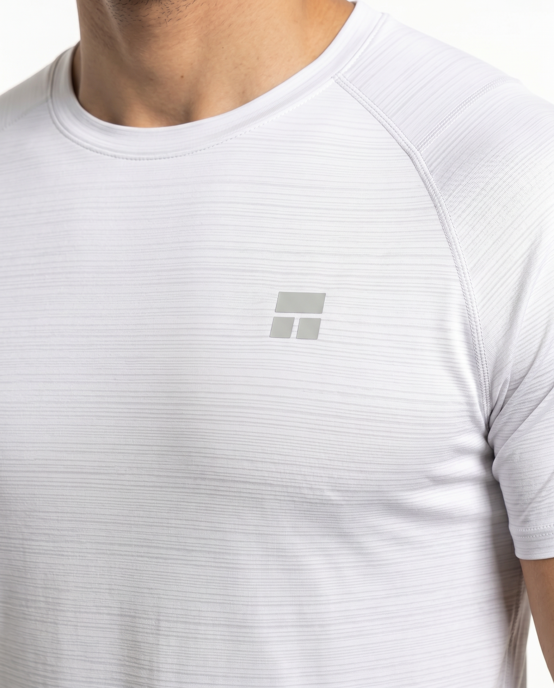 Man wearing a white t-shirt with a small logo on a white background
