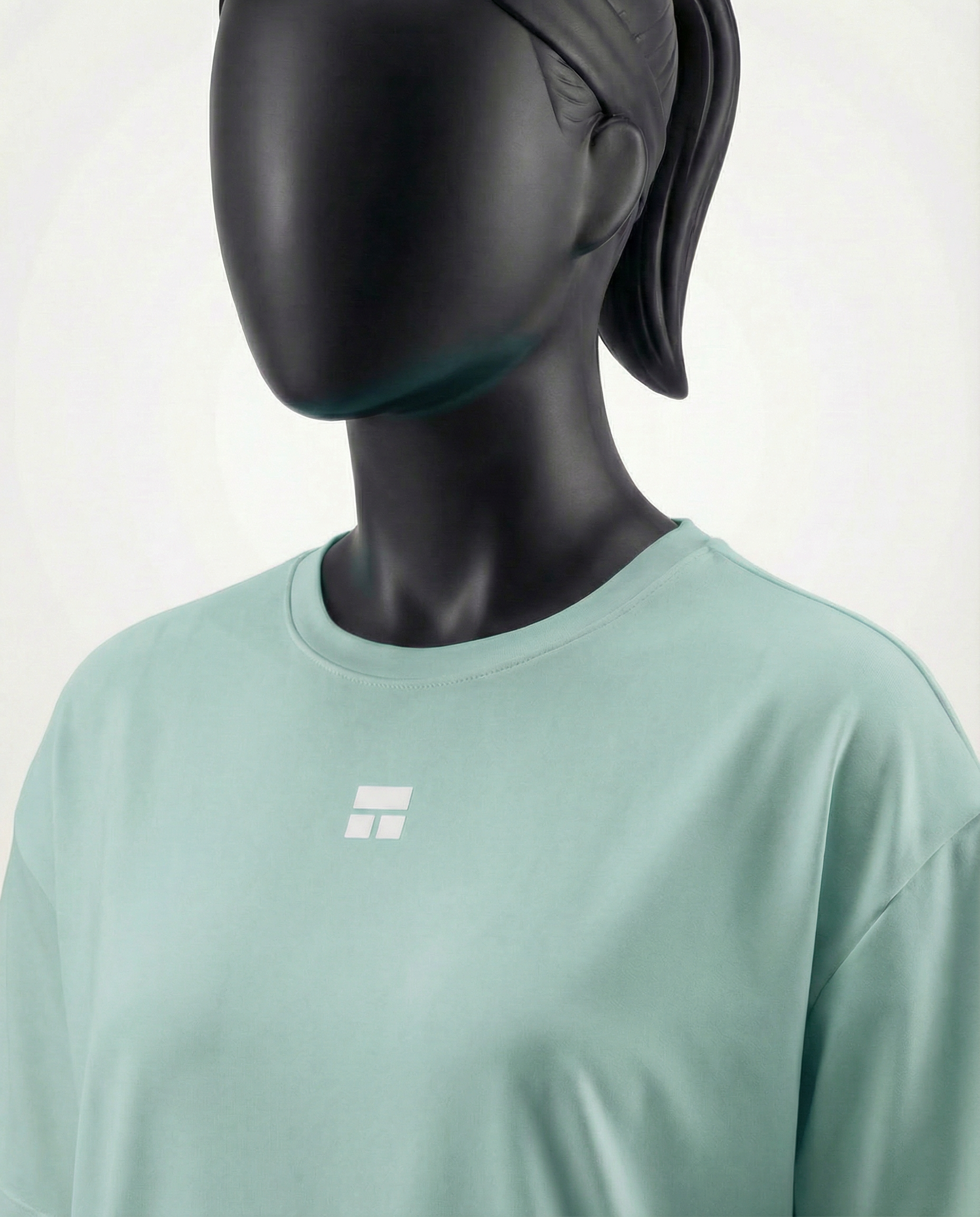 Mannequin wearing an oversized light green t-shirt on a plain background