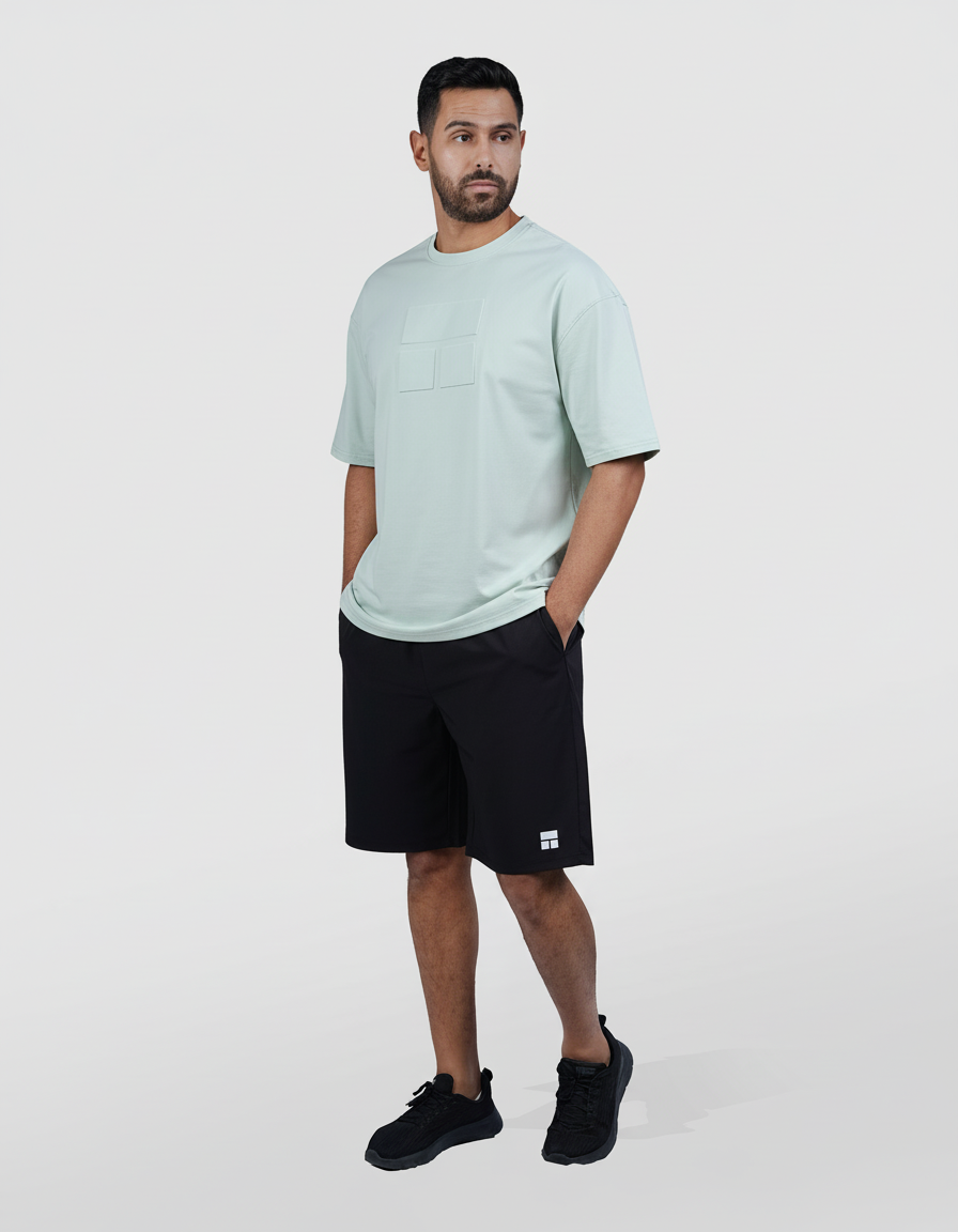 Man wearing a light blue t-shirt and black shorts on a white background