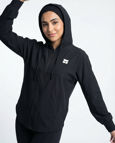 Person wearing a black hooded jacket with a logo on a white background
