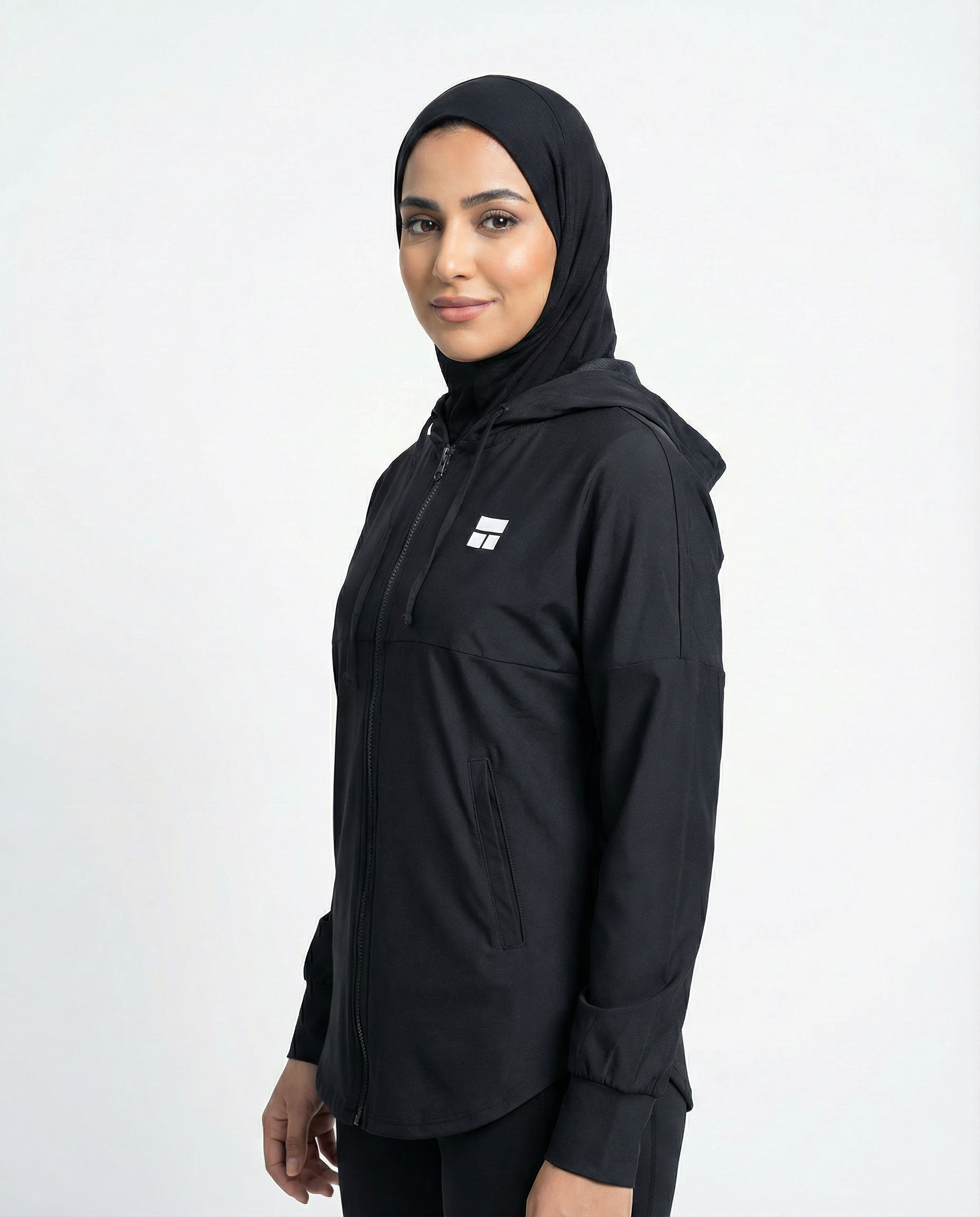 Person wearing a black hooded jacket with a logo on a white background
