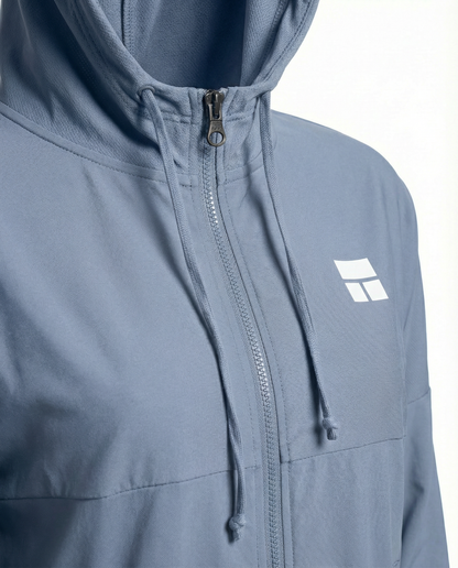 Woman wearing a light blue jacket with a logo on a white background
