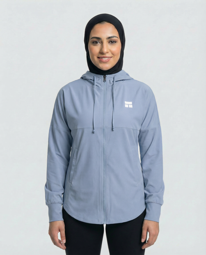 Woman wearing a light blue jacket with a logo on a white background
