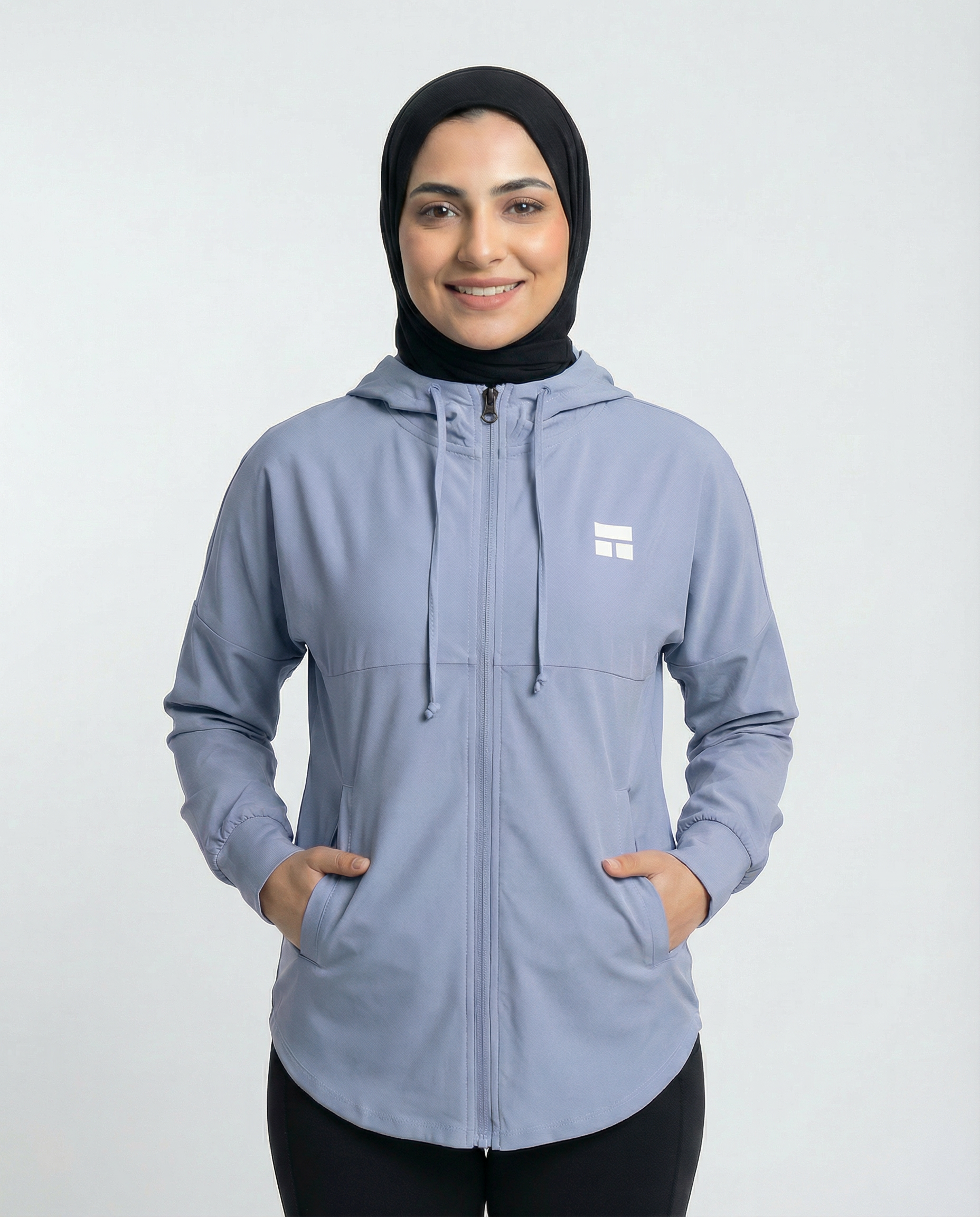 Woman wearing a light blue jacket with a logo on a white background
