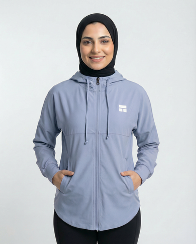 Woman wearing a light blue jacket with a logo on a white background
