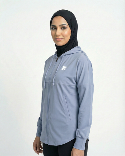 Woman wearing a light blue jacket with a logo on a white background

