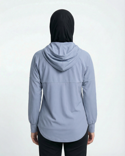 Woman wearing a light blue jacket with a logo on a white background
