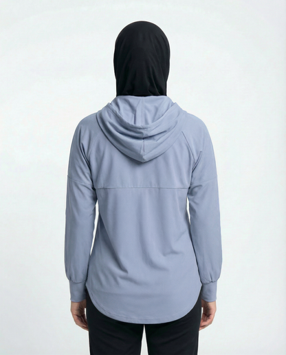 Woman wearing a light blue jacket with a logo on a white background
