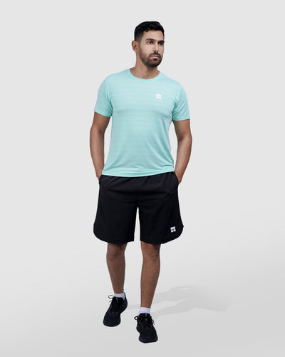 Man wearing a light blue t-shirt and black shorts on a white background
