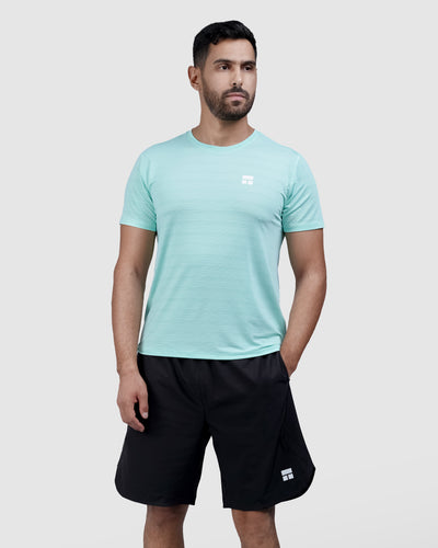 Man wearing a light blue t-shirt and black shorts on a white background
