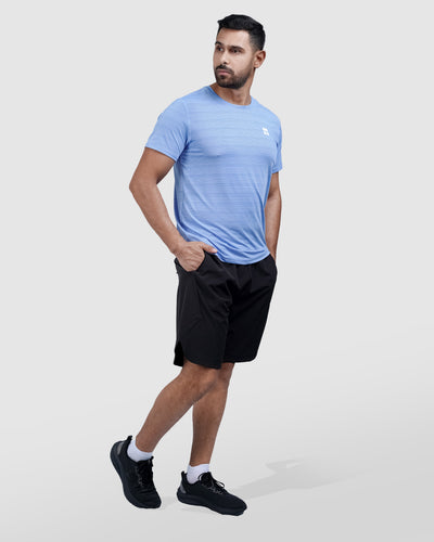 Man wearing a blue athletic shirt with a logo on a light gray background
