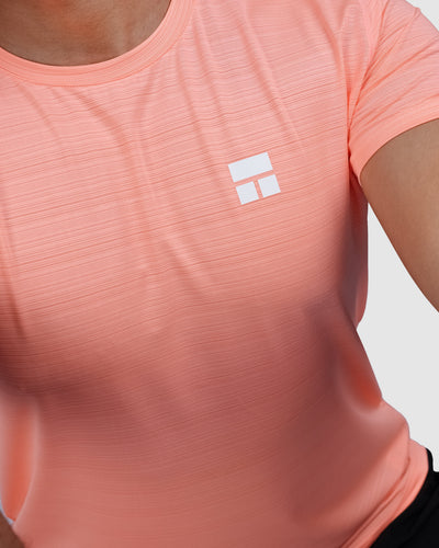 Man wearing a peach t-shirt and black shorts on a white background
