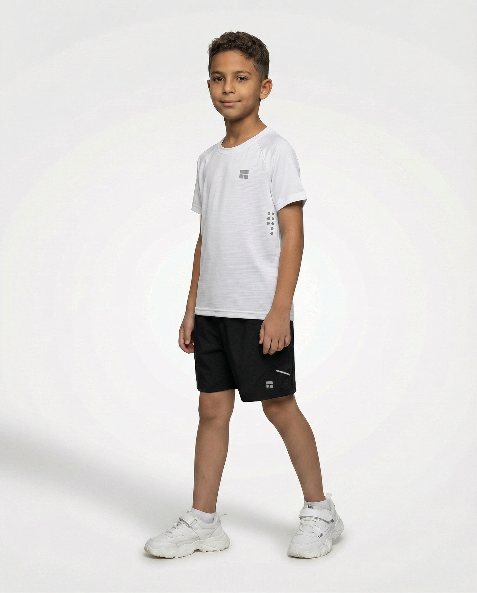 Child wearing a Courts sport white t-shirt and black shorts on a white background
#color_white