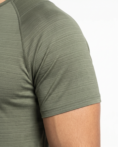 Man wearing an olive green athletic shirt on a white background
