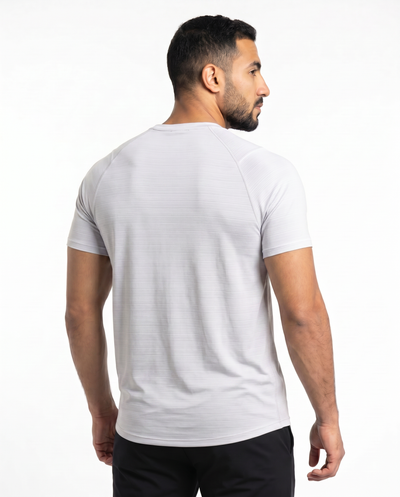 Man wearing a white t-shirt with a small logo on a white background
