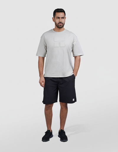 Man wearing a gray t-shirt and black shorts on a white background
