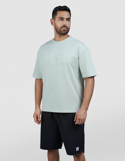 Man wearing a light blue t-shirt and black shorts on a white background

