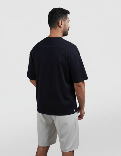 Man wearing a black t-shirt and light gray shorts on a white background

